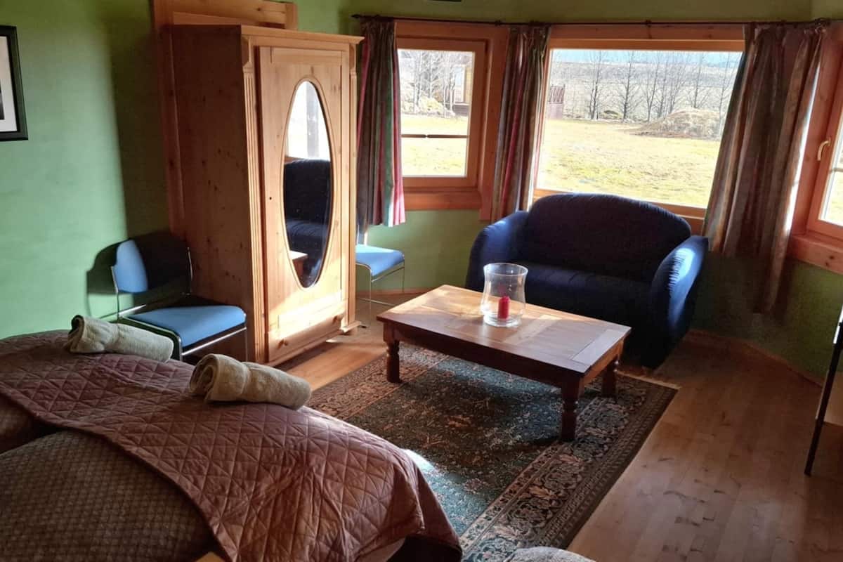 Una habitación con cama, una silla, una mesa y vistas al exterior.