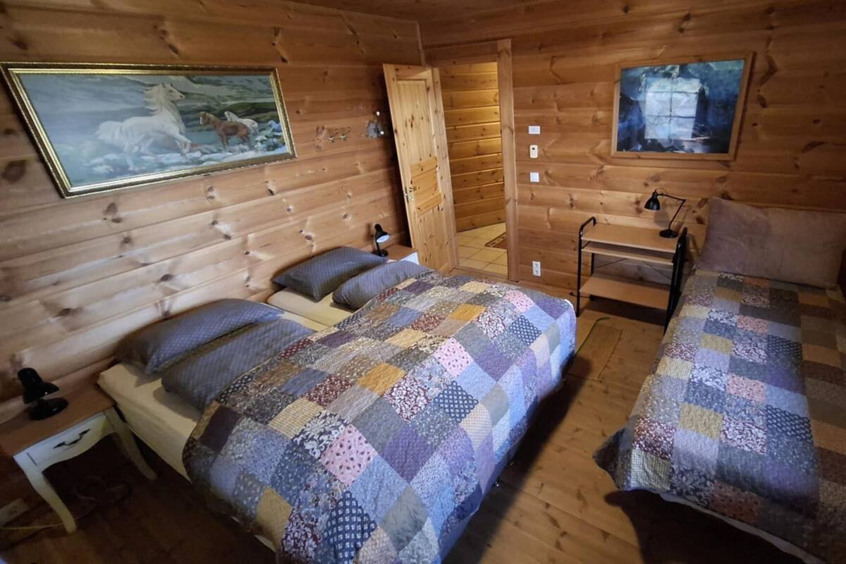 Una cabaña con dos camas de madera, una mesita de noche, una lámpara y un cuadro de un caballo.