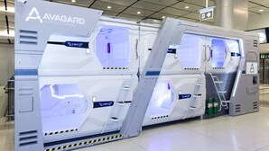 A capsule hotel with a futuristic design, featuring two large, illuminated capsules with metallic exteriors and interior lighting. - Avagard Capsule Hotel - Suvarnabhumi Airport (Bang Phli)