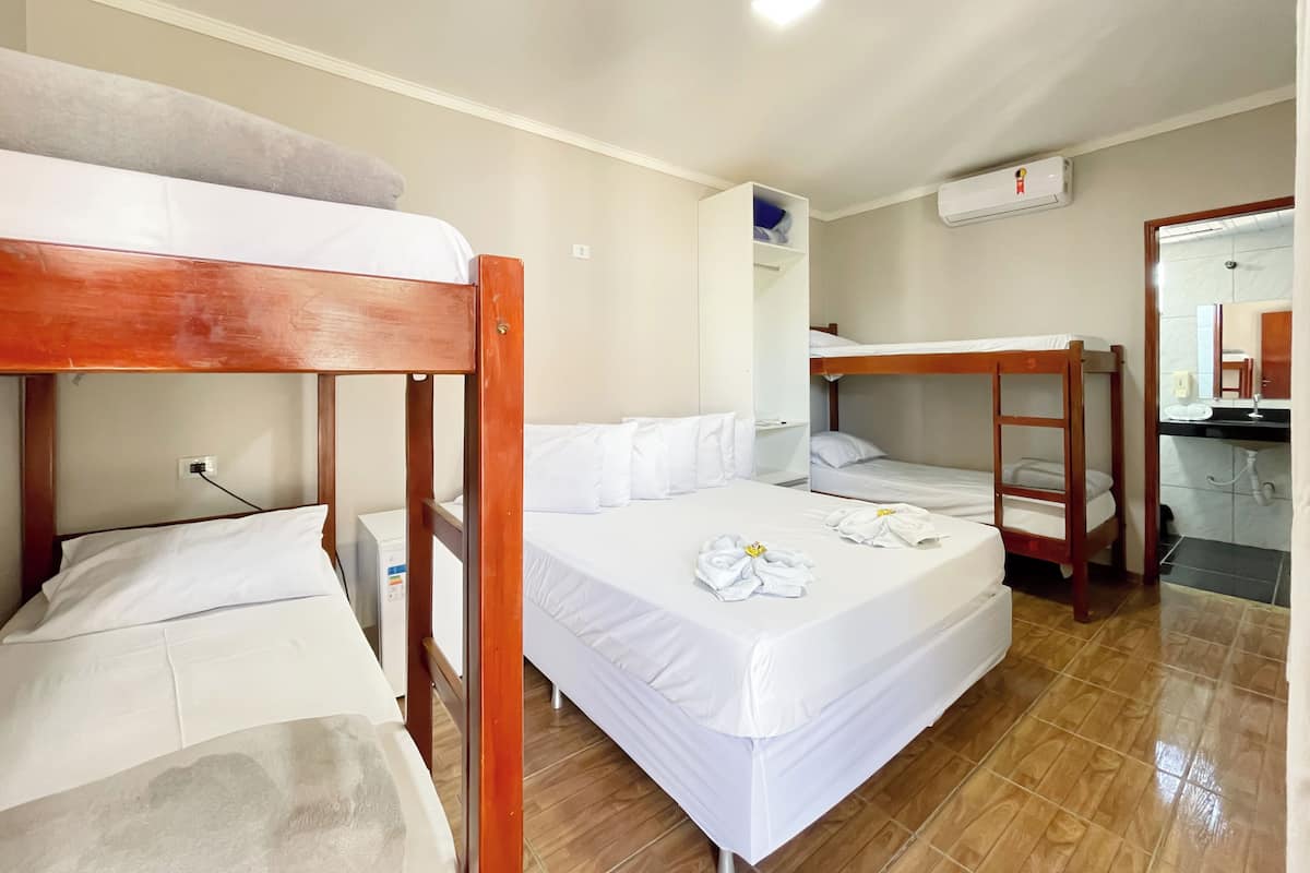 A hotel room with two bunk beds, a small desk, a mirror, and a bathroom visible through an open door.