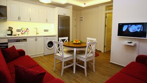 A compact living space with a kitchen, dining area, and a TV mounted on the wall. - Cesme Kale Tas Apart (Cesme)