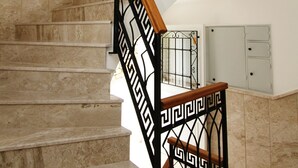 A marble staircase with black metal railings and a wooden handrail. - Cesme Kale Tas Apart (Cesme)