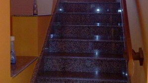 A staircase with granite steps and a handrail, leading to a room with a window and a small picture frame on the wall. - Olympus B&B (Agrigento)