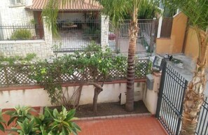 Asuinalue, jossa on kivetty patio, palmu ja aita.
