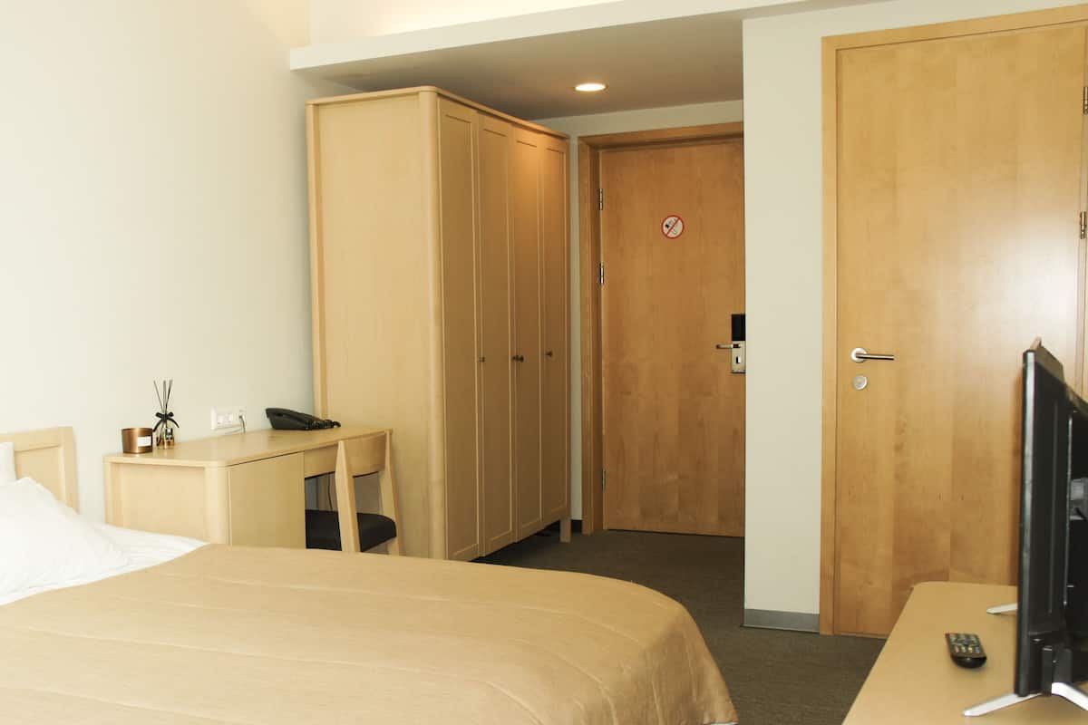 Ein Hotelzimmer mit Bett, Schreibtisch, Fernseher und Kleiderschrank.