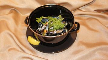 Uma tigela preta com frutos do mar sobre um fundo de tecido bege.