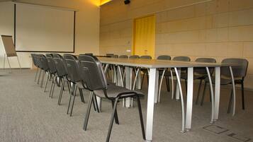 A conference room with a long table, multiple chairs, a projector screen, and a door.
