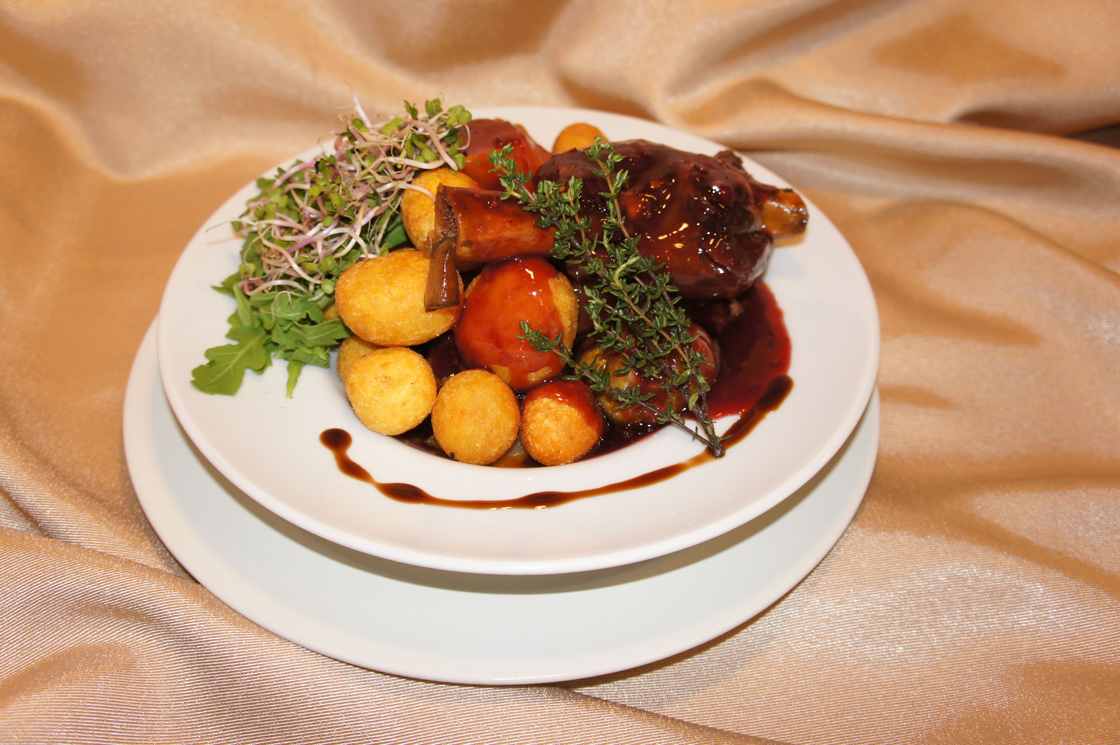 A plate of food with a meat dish, potatoes, and greens on a white plate.