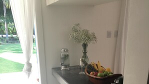 A kitchen with a fruit bowl, a vase with flowers, and a cake on a plate. - Morada Da Luz (Mata de São João)