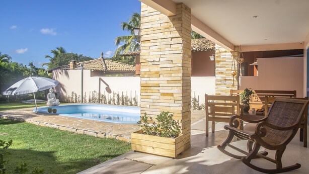 A patio area with a pool, a wooden bench, and a rocking chair. - Morada Da Luz (Mata de São João)