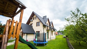 Una casa con un tobogán verde, un trampolín y un patio cercado.