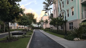 Une rue bordée d’arbres et d’immeubles, avec un bâtiment vert doté d’un balcon et un bâtiment beige surmonté d’un toit végétalisé.