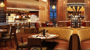 Um restaurante com mesas redondas, cabines estofadas e um espaço de bar.