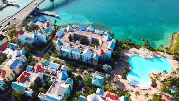 Vista aérea de um resort com vários edifícios, uma piscina e um píer.