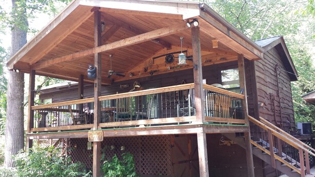 A wooden cabin with a balcony, a staircase, and a sign that reads "The Barber's".