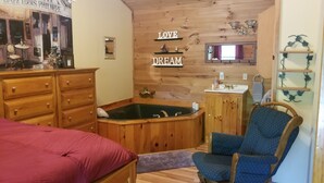 A cozy room with a wooden bathtub, a wooden dresser, a chair, and a mirror on the wall.