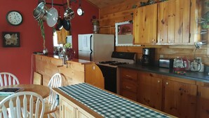 A kitchen with wooden cabinets, a refrigerator, a stove, and various kitchen utensils hanging above.