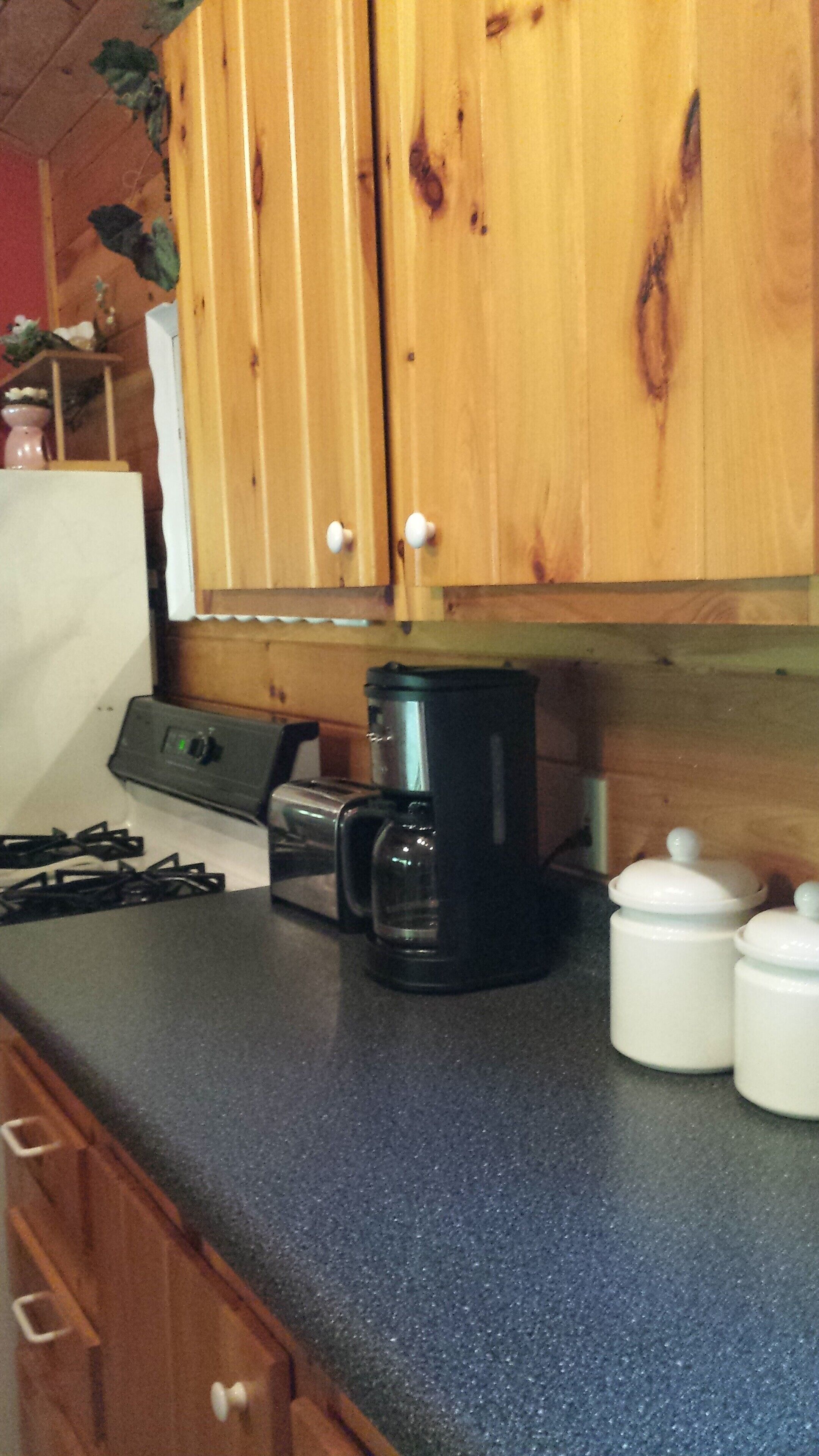A kitchen with wooden cabinets, a black coffee maker, a toaster, and two white containers.