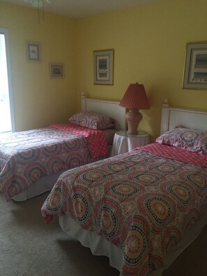 Ein Zimmer mit zwei Betten, jeweils mit gemusterten Bettbezügen und einem Nachttisch mit Lampe.