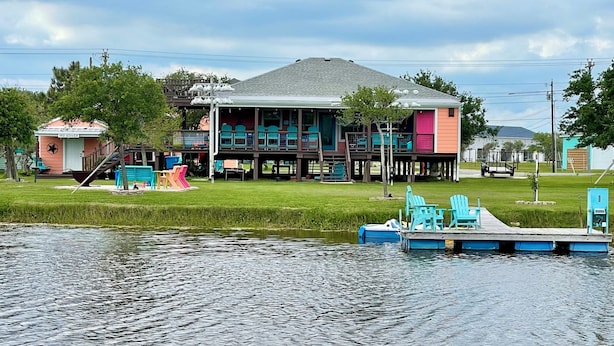 Ein Haus mit Steg und Stühlen am Wasser.