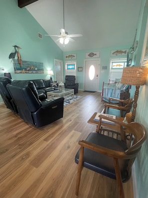 A living room with a black leather sofa, a wooden coffee table, and a ceiling fan.