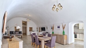Amplia sala de estar con una mesa de comedor, sillas moradas, una mesa de centro de madera y un candelabro.