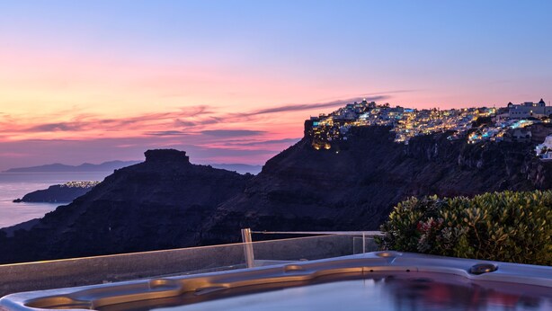 Un jacuzzi con vistas a un pueblo costero al atardecer.