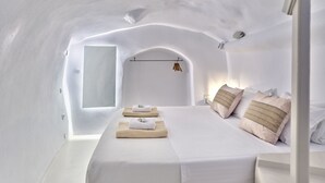 Una habitación blanca con arco, con una cama, toallas y un perchero.