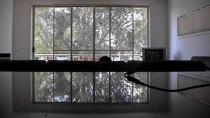 A room with a large window, a bed, and a small table with a picture frame.