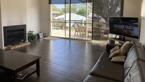 A modern living room with a fireplace, a television, and a sliding glass door leading to an outdoor patio.
