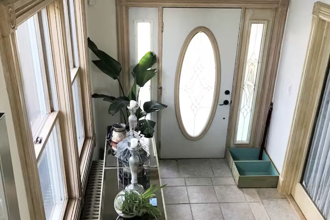 Um corredor com uma porta, uma planta em vaso e um banco.