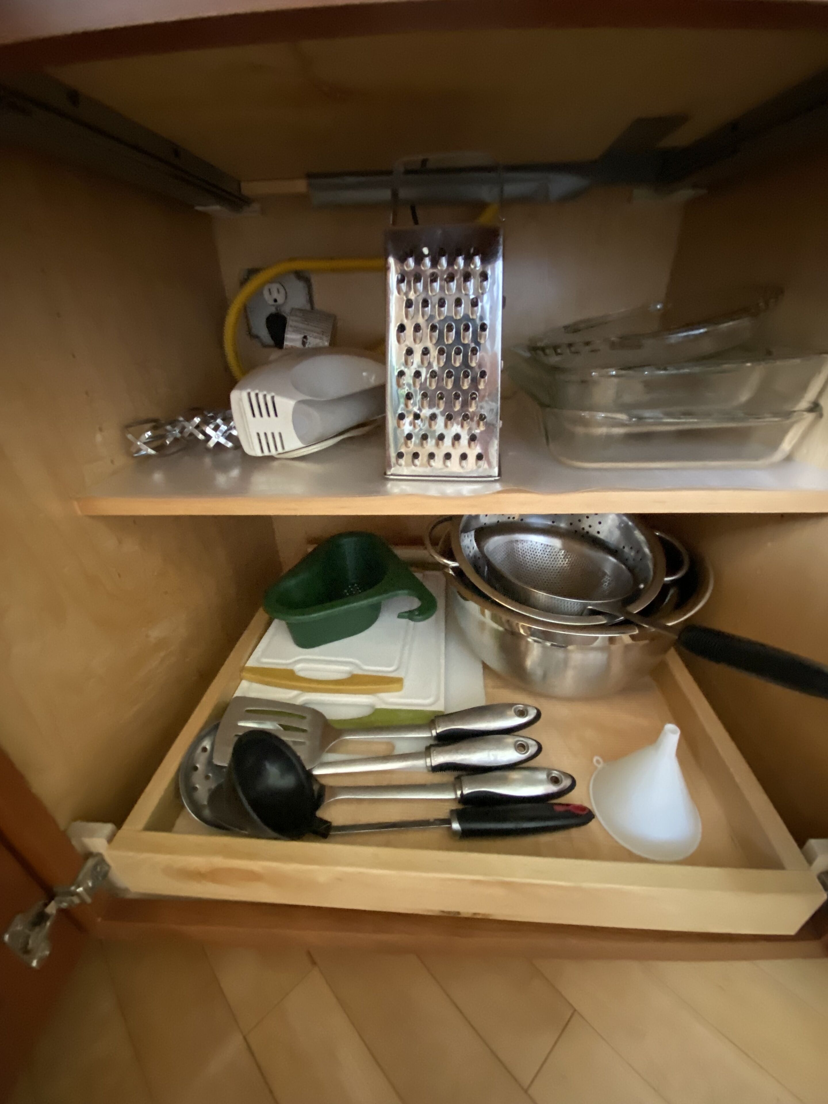 A kitchen with a wooden countertop, a grater, a colander, a strainer, and various kitchen utensils.