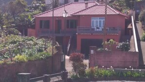 Um edifício vermelho com telhado ladrilhado, varanda e escadaria que leva a um andar superior.