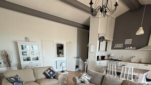 Un salon spacieux avec deux canapés, une table basse et un coin repas, la cuisine étant située à l’arrière-plan.