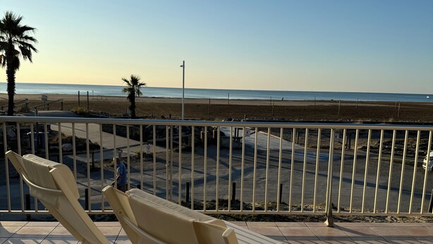 Une terrasse avec des chaises longues donnant sur une plage.