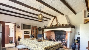 Een klassieke kamer met een bed, een bank, een open haard en diverse decoratieve objecten.