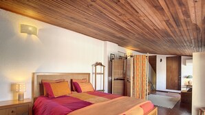 Een slaapkamer met een houten plafond, een bed met een houten hoofdeinde en een nachtkastje met een lamp.