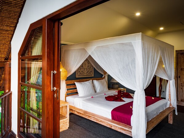 A four-poster bed with a canopy, wooden headboard, and a nightstand with a lamp.