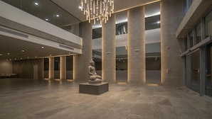 A spacious lobby with a large Buddha statue, high ceilings, and modern lighting.