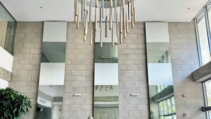 A modern interior with a Buddha statue, large reflective panels, and a unique hanging light fixture.