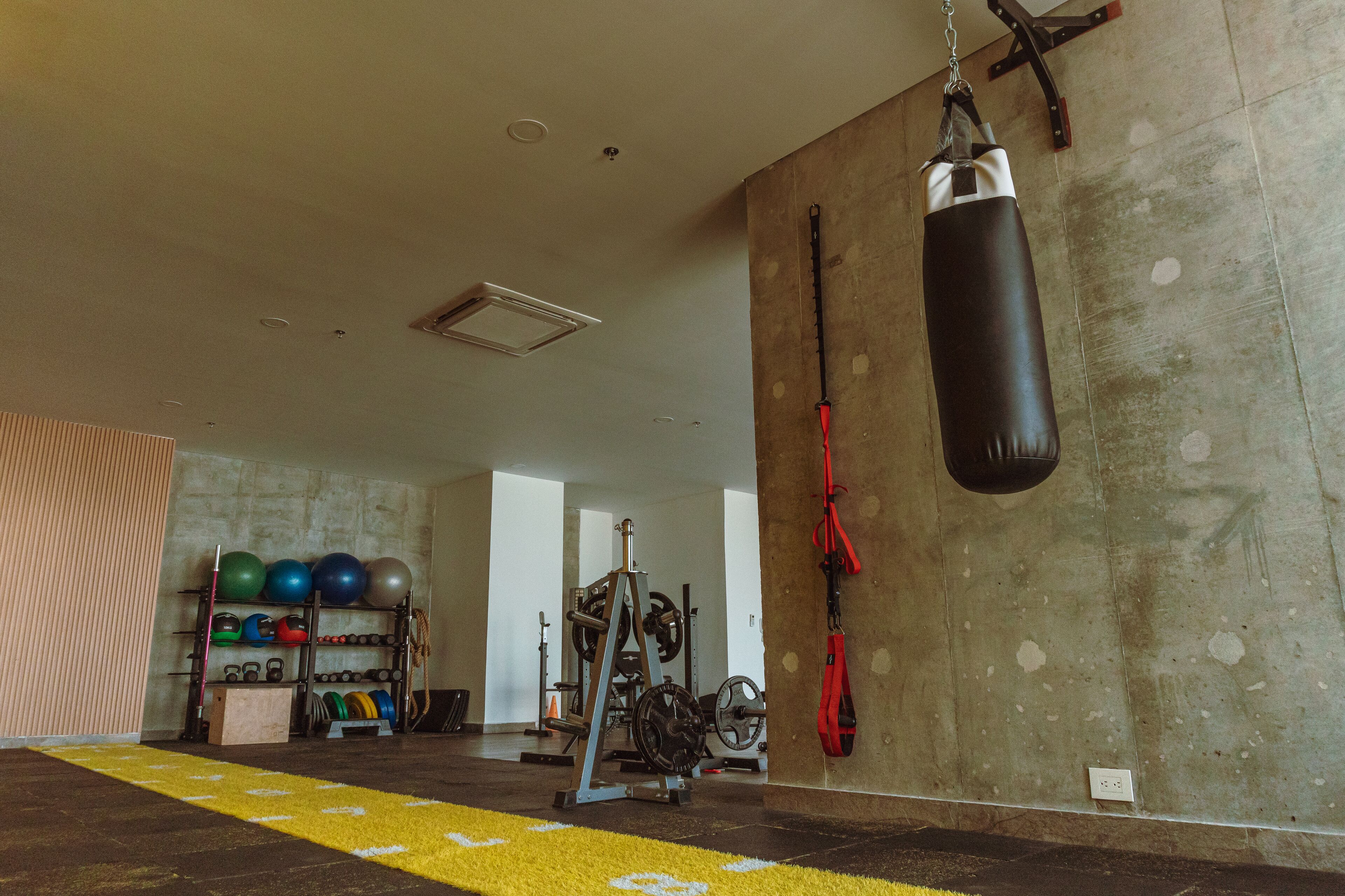 A gym with a punching bag, weightlifting equipment, and exercise balls.