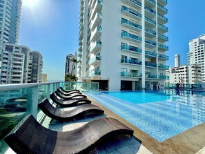 A rooftop swimming pool with lounge chairs, surrounded by high-rise buildings. - Top Apartment Cartagena Colombia (Cartagena)