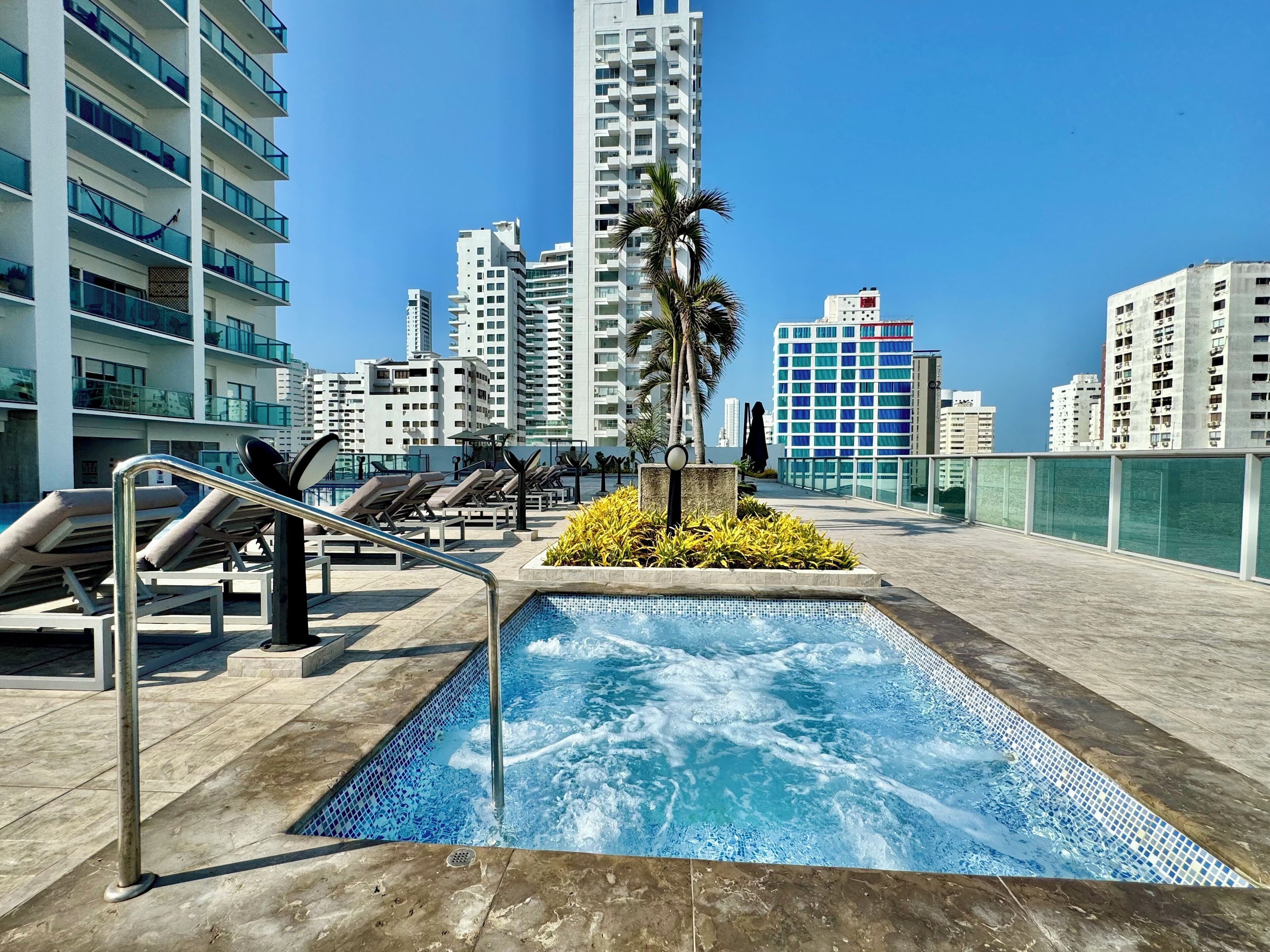 Une piscine sur le toit, dotée de chaises longues et offrant une vue sur les gratte-ciel.