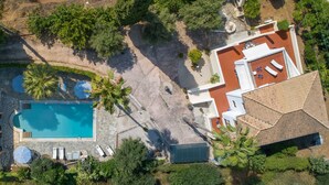 Vista aérea de una propiedad con piscina, tumbonas y un porche cubierto.