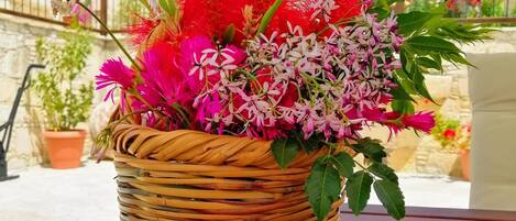 A wicker basket filled with vibrant flowers on a wooden table.