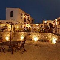 Un patio exterior con suelo de piedra, muebles de madera y plantas en macetas.