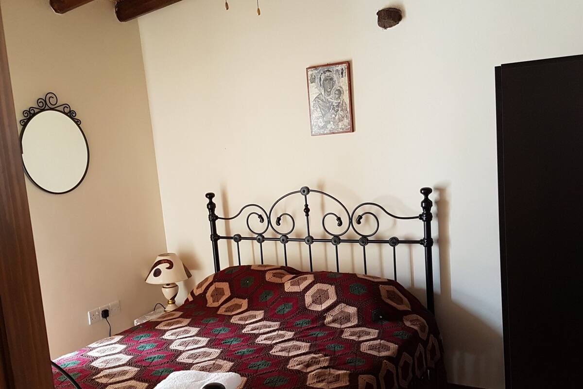 A bedroom with a bed, a round mirror, a framed picture, and a door.