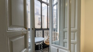 Una habitación con una puerta blanca, una mesita redonda pequeña y una silla de mimbre.