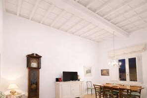 A dining area with a wooden table, chairs, a clock, a television, and a chandelier. - The emotion of living in a Renaissance palace in the heart of Florence (Firenze)