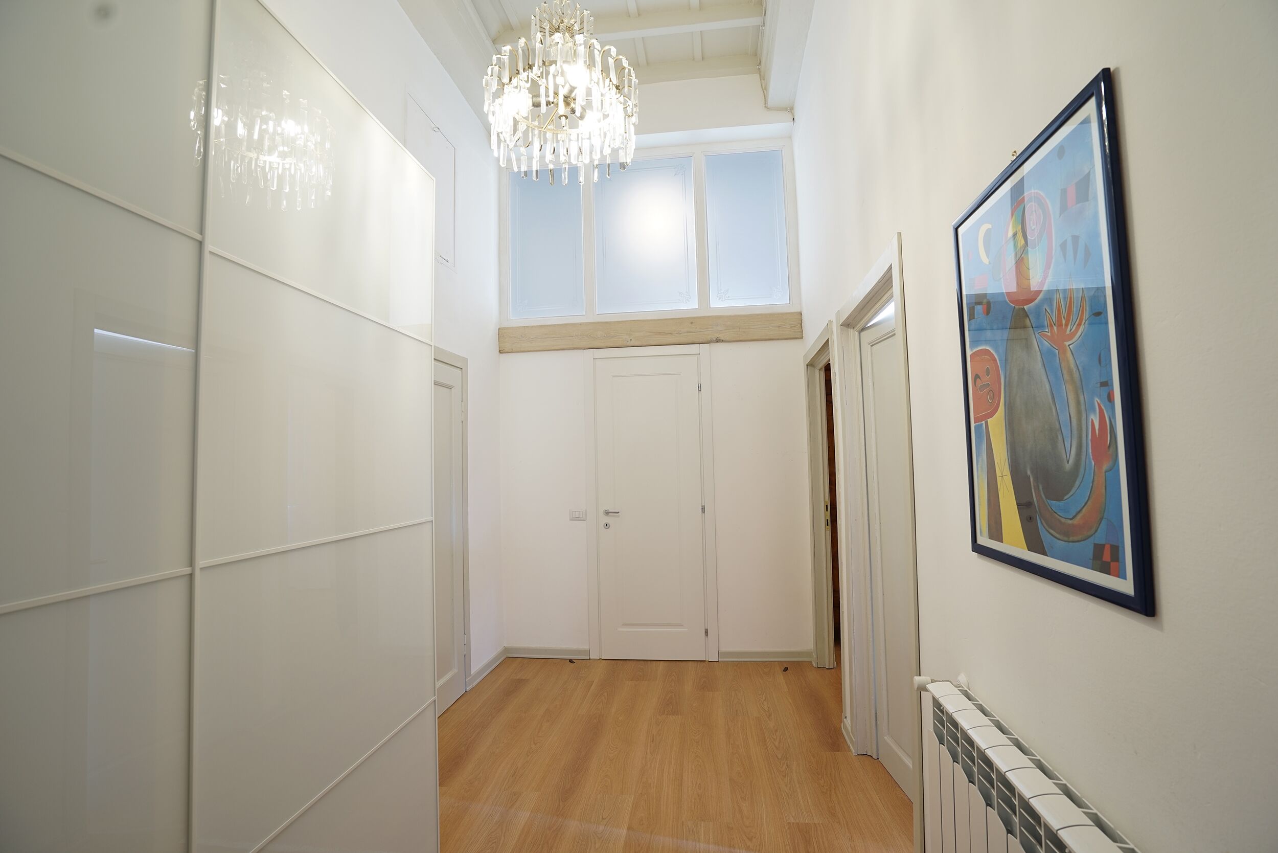 Ein Flur mit einer Kandelaber, einer Tür und einem gerahmten abstrakten Gemälde an der Wand.